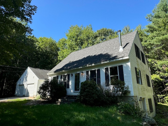 new england style home featuring an outbuilding, a front yard, and a garage