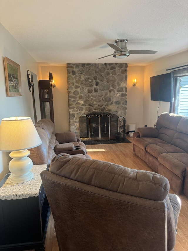 265 Main Rd, Bradford, ME 04410 - living room featuring a textured ceiling, a stone fireplace, wood finished floors, and a ceiling fan