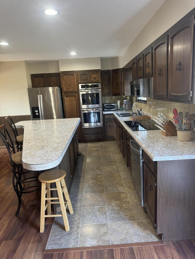 265 Main Rd, Bradford, ME 04410 - kitchen featuring dark brown cabinetry, a kitchen island, a breakfast bar area, stainless steel appliances, and light countertops