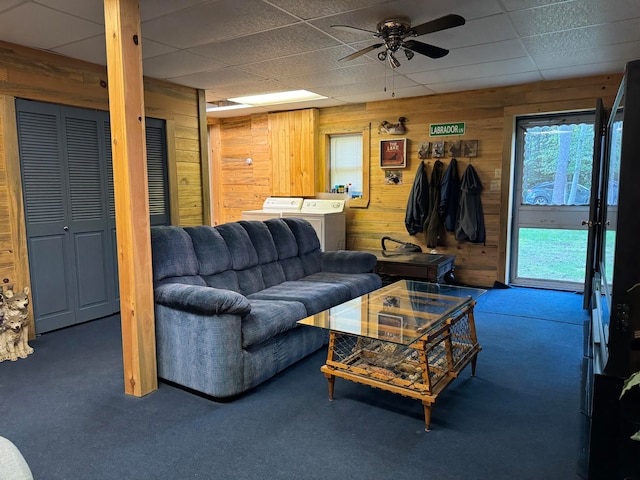 living room with carpet floors, washer and dryer, ceiling fan, and wooden walls