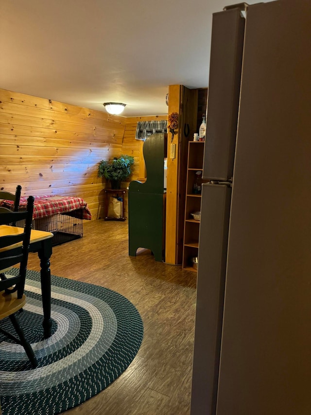 bedroom featuring wood walls, hardwood / wood-style floors, and fridge