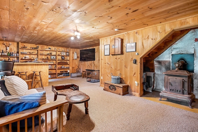 living room with a wood stove, wood walls, and wooden ceiling