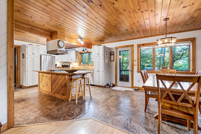 kitchen featuring pendant lighting, hardwood / wood-style flooring, stainless steel refrigerator, and white cabinets