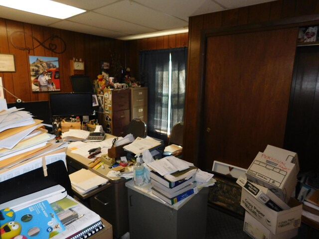 office space with wood walls and a drop ceiling