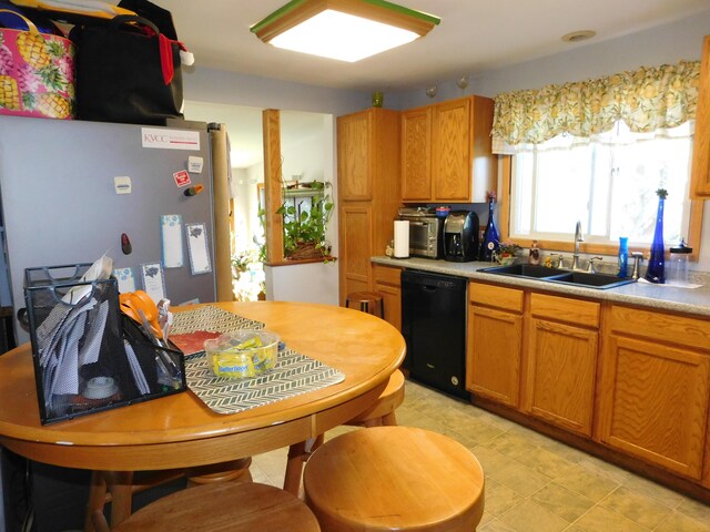 kitchen featuring black dishwasher, stainless steel fridge, and sink