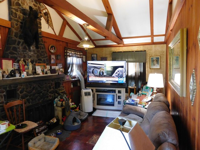 living room featuring lofted ceiling with beams, wooden walls, and a stone fireplace