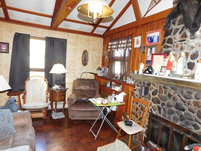 living room featuring a stone fireplace and lofted ceiling with beams