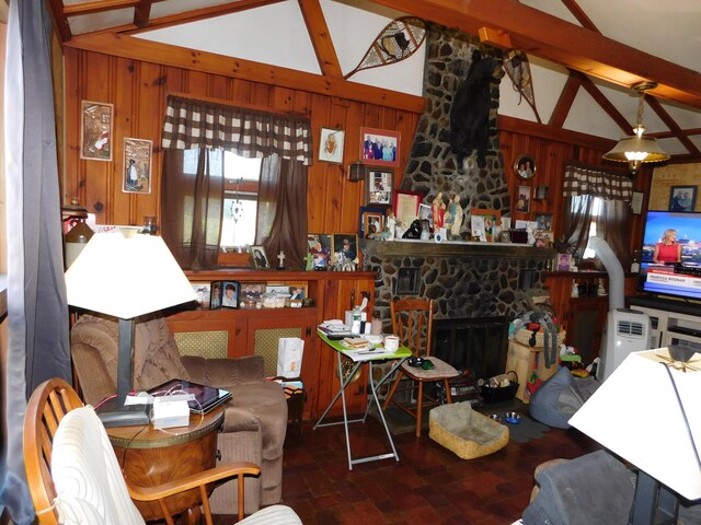 living room featuring wood walls, beamed ceiling, and a fireplace