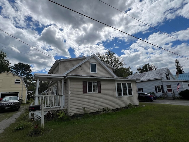 bungalow featuring a garage, a front yard, covered porch, and an outbuilding