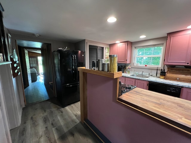 kitchen with black appliances, sink, wood counters, and hardwood / wood-style flooring