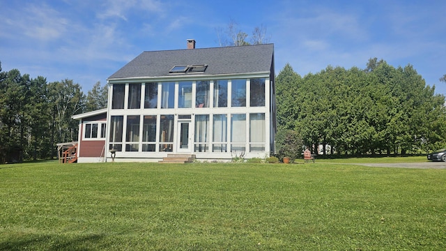 back of house featuring a sunroom and a lawn