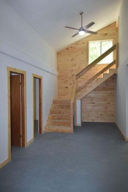 additional living space with high vaulted ceiling, ceiling fan, wooden walls, and carpet floors