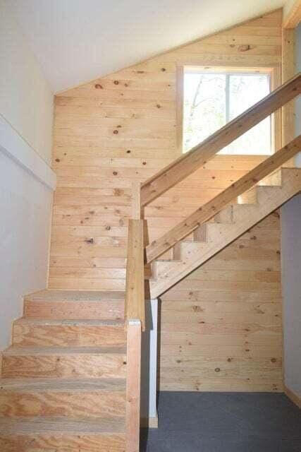 staircase with lofted ceiling and wooden walls