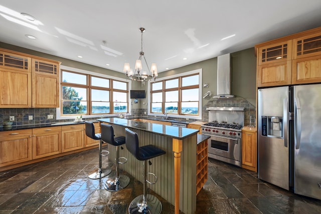 kitchen featuring wall chimney exhaust hood, a center island, a healthy amount of sunlight, and stainless steel appliances