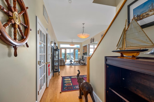 hall with french doors and light hardwood / wood-style flooring