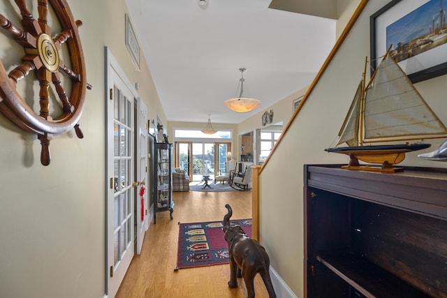corridor with baseboards, visible vents, light wood-style flooring, and french doors