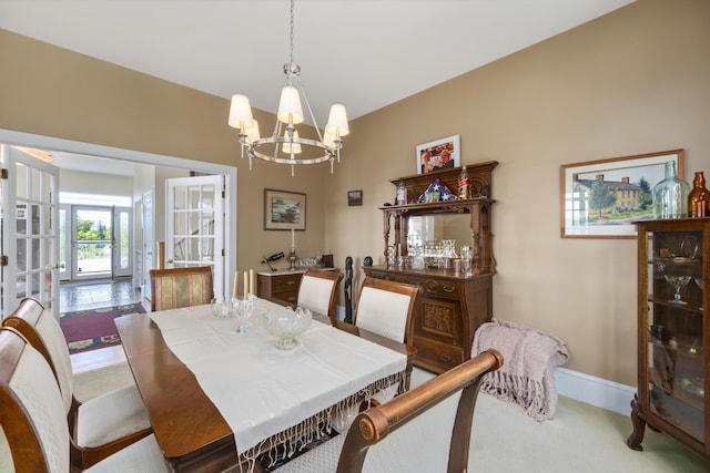 carpeted dining area with baseboards and a notable chandelier