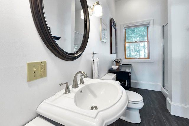 bathroom featuring toilet, sink, an enclosed shower, and wood-type flooring