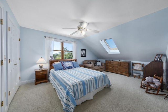 carpeted bedroom with baseboards, lofted ceiling with skylight, and a ceiling fan