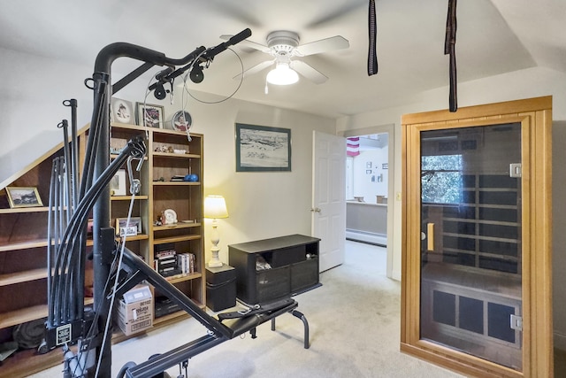 exercise room with baseboard heating, carpet flooring, and a ceiling fan
