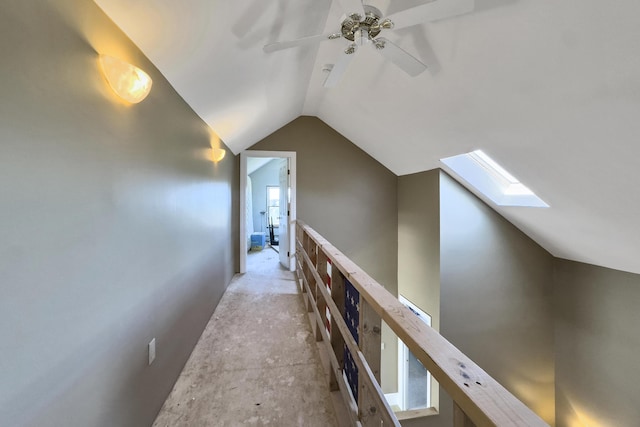 hallway with an upstairs landing and vaulted ceiling with skylight