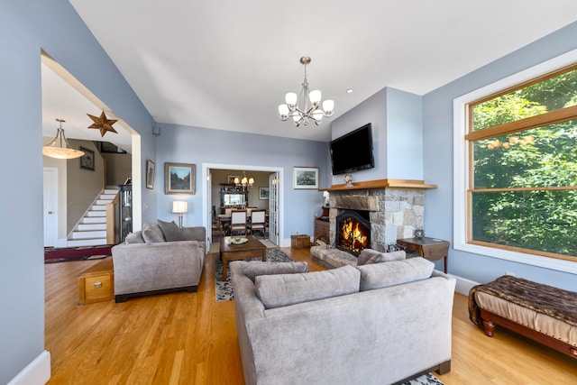 living room with a fireplace, light wood-type flooring, and an inviting chandelier