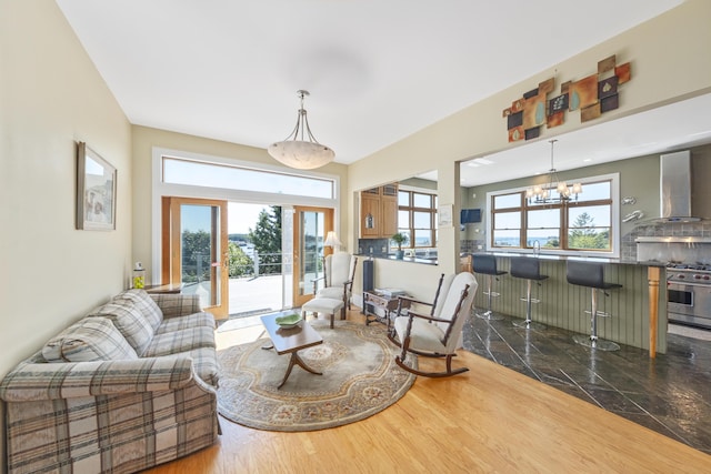 living area with dark wood finished floors, a wealth of natural light, and a chandelier