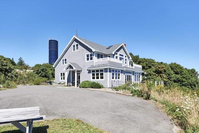shingle-style home with a balcony and a chimney