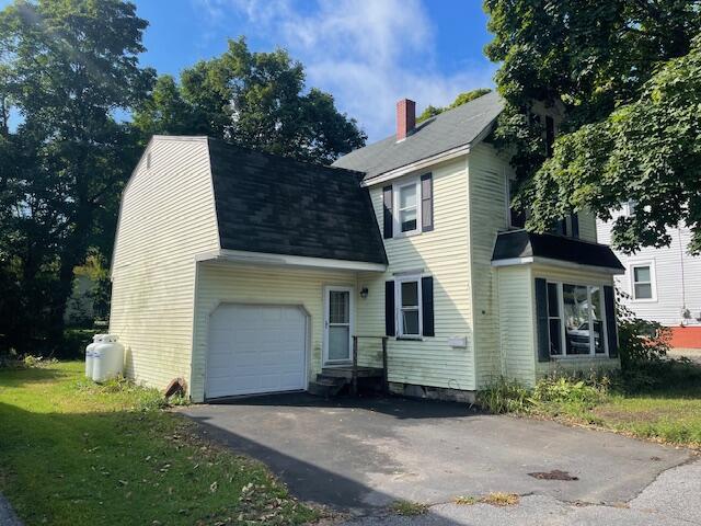 view of front of home featuring aphalt driveway, a garage, a gambrel roof, roof with shingles, and a front lawn