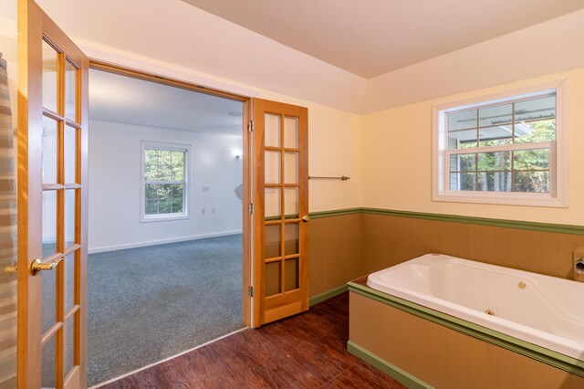 bathroom with french doors, hardwood / wood-style flooring, and a washtub