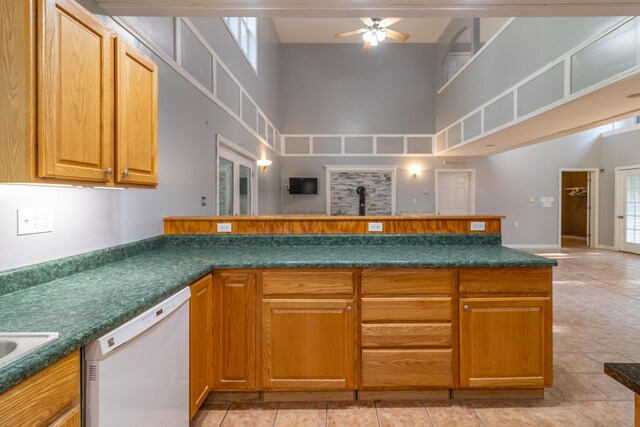 kitchen featuring a towering ceiling, dishwasher, ceiling fan, and light tile patterned floors