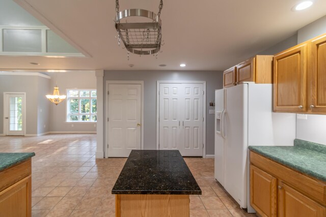 kitchen featuring white refrigerator with ice dispenser, an inviting chandelier, light tile patterned flooring, and a kitchen island