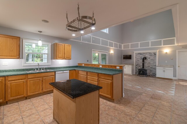 kitchen featuring a kitchen island, dishwasher, a towering ceiling, a wood stove, and sink