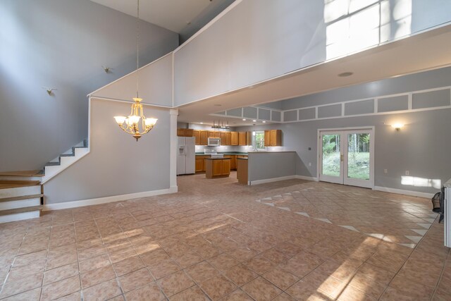 unfurnished living room with an inviting chandelier, a high ceiling, and light tile patterned floors