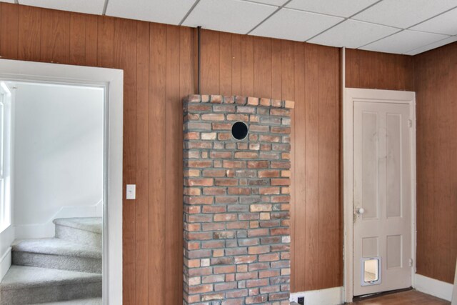 interior space featuring wooden walls and a drop ceiling