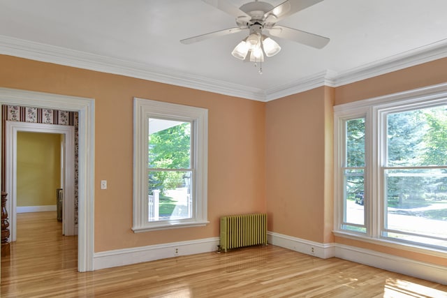 spare room with ceiling fan, ornamental molding, radiator heating unit, and light wood-type flooring