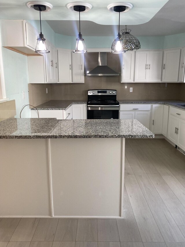 kitchen with dark stone counters, wall chimney exhaust hood, white cabinetry, and stainless steel range with electric stovetop