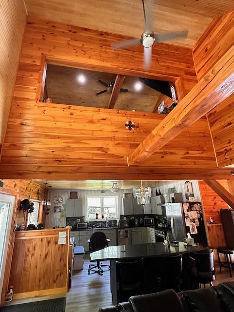 kitchen with wooden walls, lofted ceiling with beams, wooden ceiling, dark wood-style flooring, and freestanding refrigerator