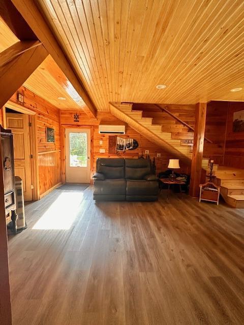 living area with stairs, wood walls, wooden ceiling, and wood finished floors