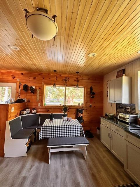 bedroom featuring dark wood-type flooring, wood ceiling, multiple windows, and wooden walls