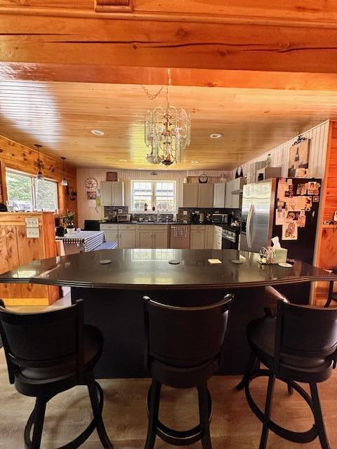 bar featuring wooden ceiling, plenty of natural light, and stainless steel refrigerator with ice dispenser