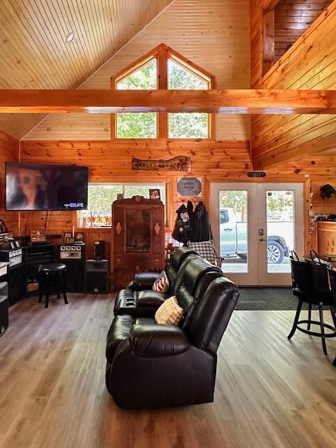 living area featuring light wood-style floors, wooden ceiling, french doors, wood walls, and high vaulted ceiling