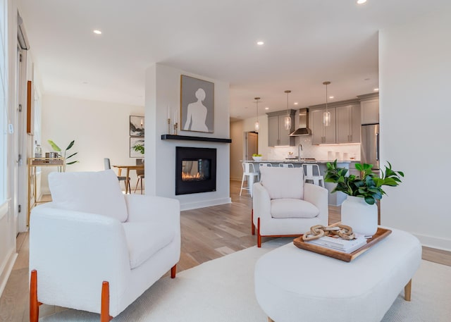 living room with light hardwood / wood-style flooring, sink, and a multi sided fireplace