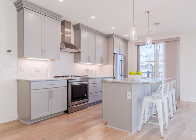 kitchen with wall chimney exhaust hood, gray cabinets, and appliances with stainless steel finishes