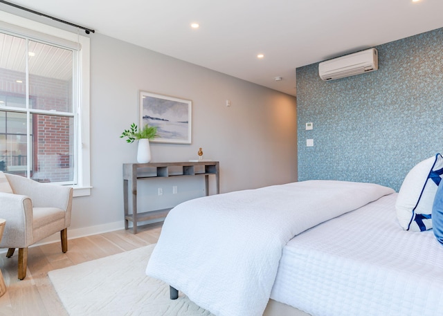 bedroom featuring a wall mounted air conditioner, light wood-style flooring, recessed lighting, baseboards, and an accent wall