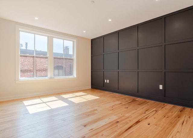 unfurnished bedroom with recessed lighting, light wood-style floors, and a decorative wall