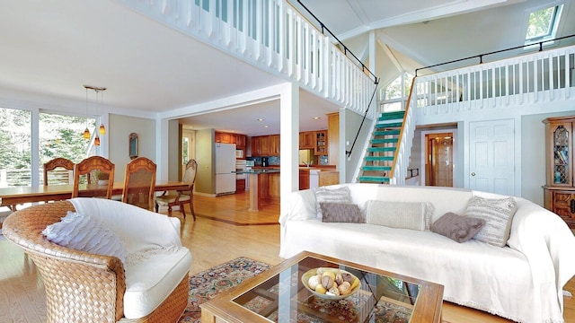 living room featuring a towering ceiling, a wealth of natural light, and light hardwood / wood-style flooring