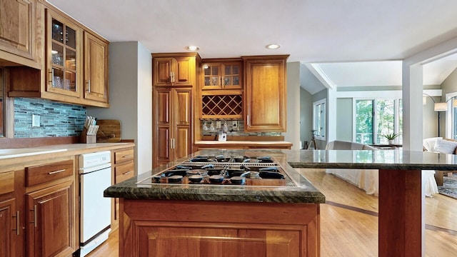 kitchen with decorative backsplash, light wood-type flooring, stainless steel gas stovetop, and dark stone counters