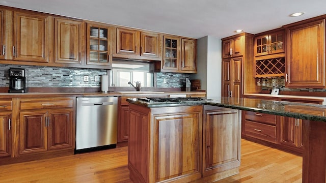 kitchen with a center island, dark stone countertops, decorative backsplash, appliances with stainless steel finishes, and light wood-type flooring