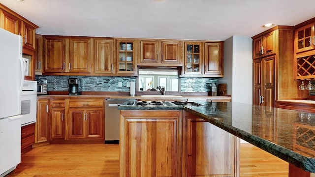 kitchen featuring appliances with stainless steel finishes, tasteful backsplash, sink, dark stone countertops, and light hardwood / wood-style floors